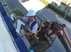 A man in white hard hat on a crane.