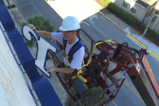 A man in white hard hat on a crane.